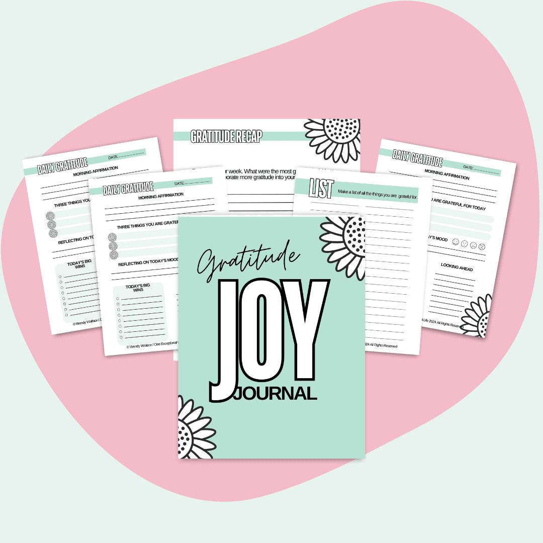This is a mockup of Gratitude Joy Journal Workbook in the center. Surrounding the cover are several open pages from the workbook. The workbook cover and pages are decorated with floral designs, and the background is a soft pink abstract shape on a lighter pink base.